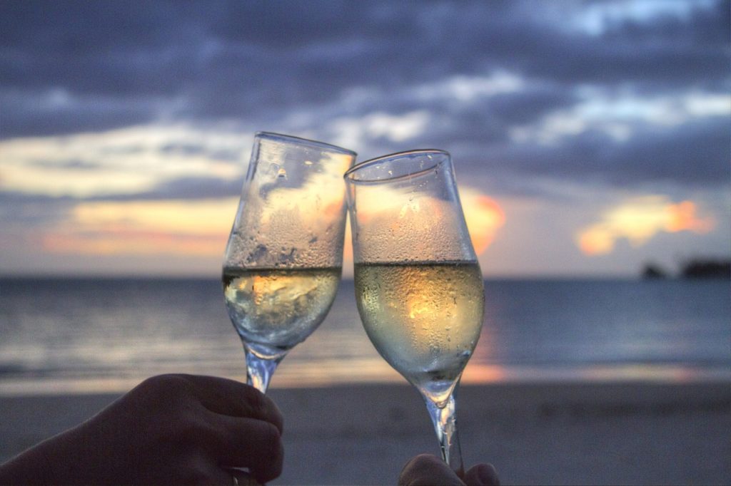 Two champagne glasses on a beach at sunset